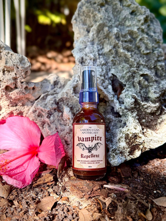 Vampire Repellent Non-Toxic Herbal Bug Spray in front of a rock with a pink flower.