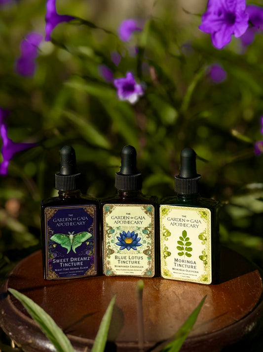 Three tincture bottles on a wooden surface with purple flowers in the background. immunity and vitality tincture, mood boosting tincture, sleep tincture.