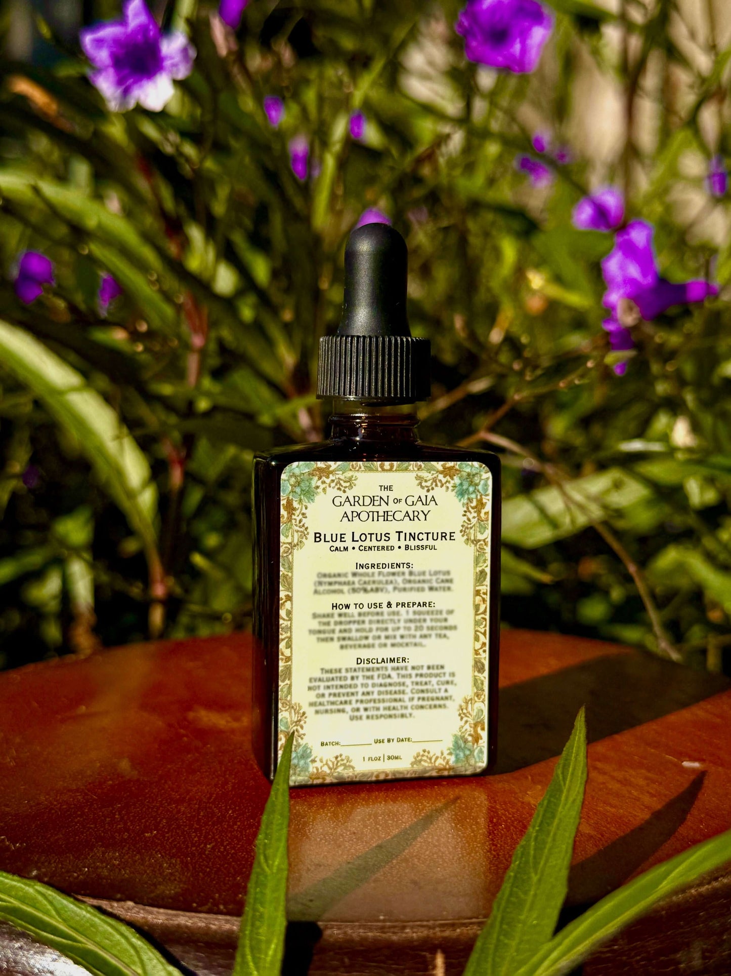 Bottle of 'Garden of Gaia Apothecary' tincture on a wooden surface with greenery in the background
