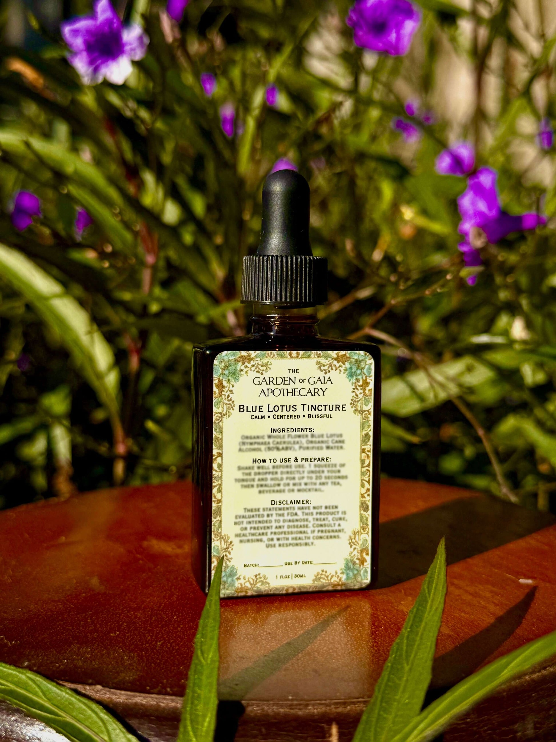 Bottle of 'Garden of Gaia Apothecary' tincture on a wooden surface with greenery in the background