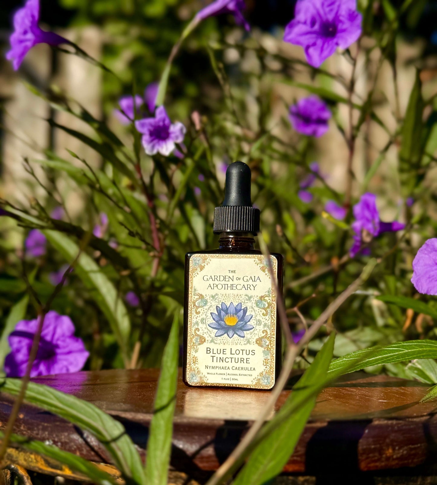 Bottle of Blue Lotus Tincture with a decorative label on a wooden surface surrounded by purple flowers.