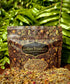 Golden Treasures-herbal smoke blend package surrounded by herbal ingredients on a wooden surface.