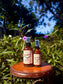 Vampire Repellent Non-Toxic Herbal Bug Spray bottles displayed outdoors among greenery.