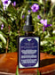 Sweet Dreamz Tincture-Nervous System Relaxation Elixir bottle in a garden setting with flowers.