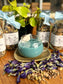 Tea with blue liquid and butterfly pea flowers on a wooden surface with bottles of tea leaves in the background.