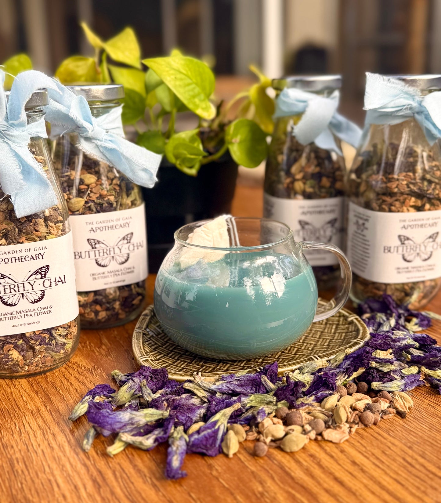 Butterfly Chai tea jars with a teapot filled with blue liquid on a wooden surface.