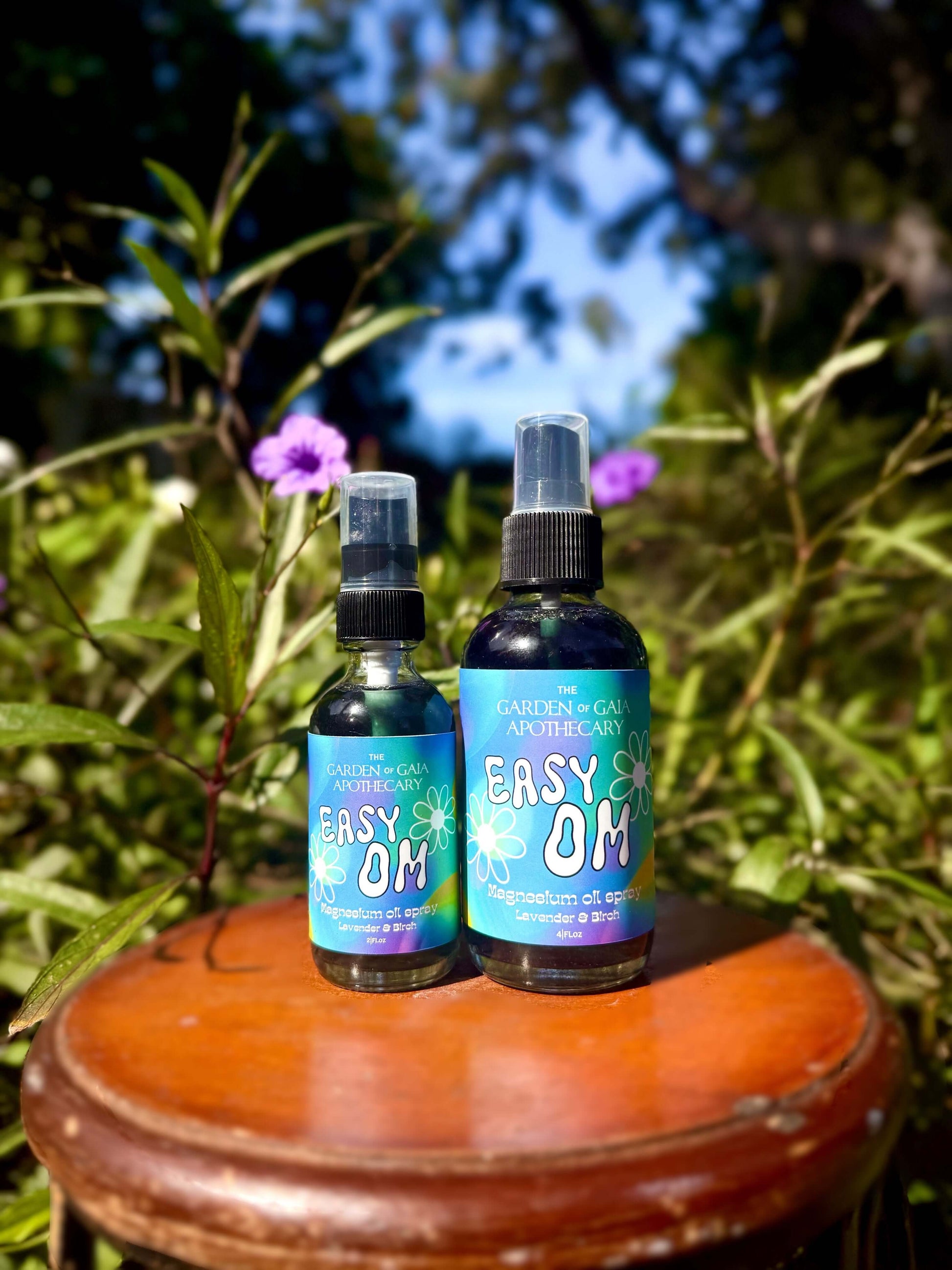 Easy OM-Magnesium Fine Mist Spray bottles on a wooden stool surrounded by greenery and flowers.