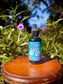 Easy OM-Magnesium Fine Mist Spray bottle on wooden surface surrounded by greenery and flowers.