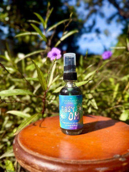Easy OM-Magnesium Fine Mist Spray bottle placed on wooden surface surrounded by greenery.
